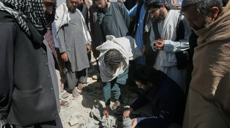 Residents and Taliban police gather the remains of a projectile at the site of a strike in Kabul, Afghanistan
