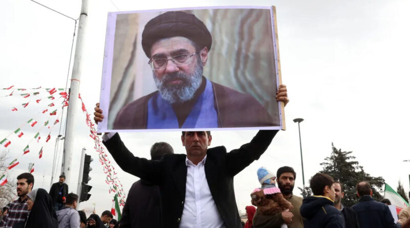 man holding Mojtaba Khamenei's photo